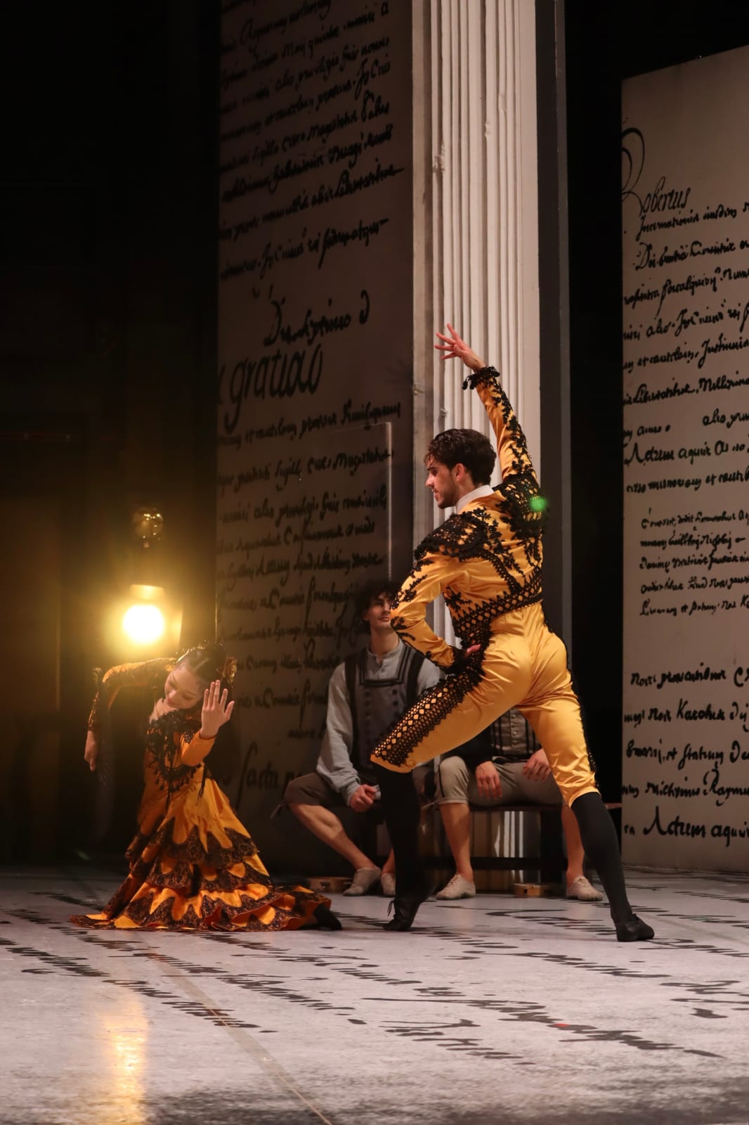 Scene from Don Quixote: Espada in a yellow and black embroidered toreador costume strikes a pose beside a dancer in a yellow dress